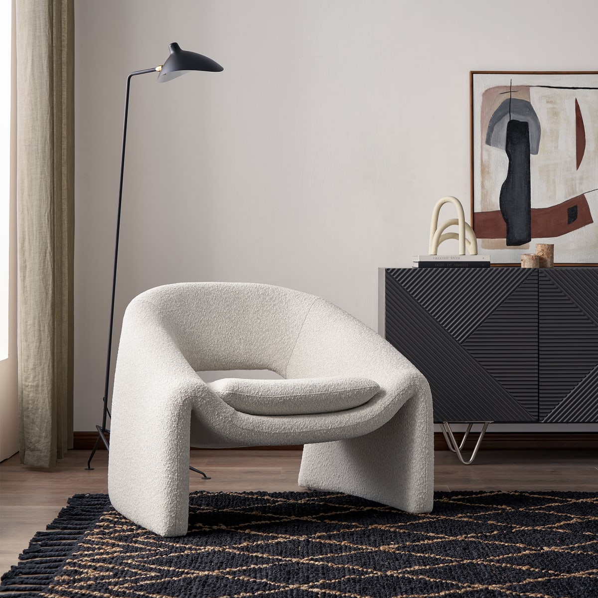 Modern gray armchair in a stylish living room with abstract art and a floor lamp.