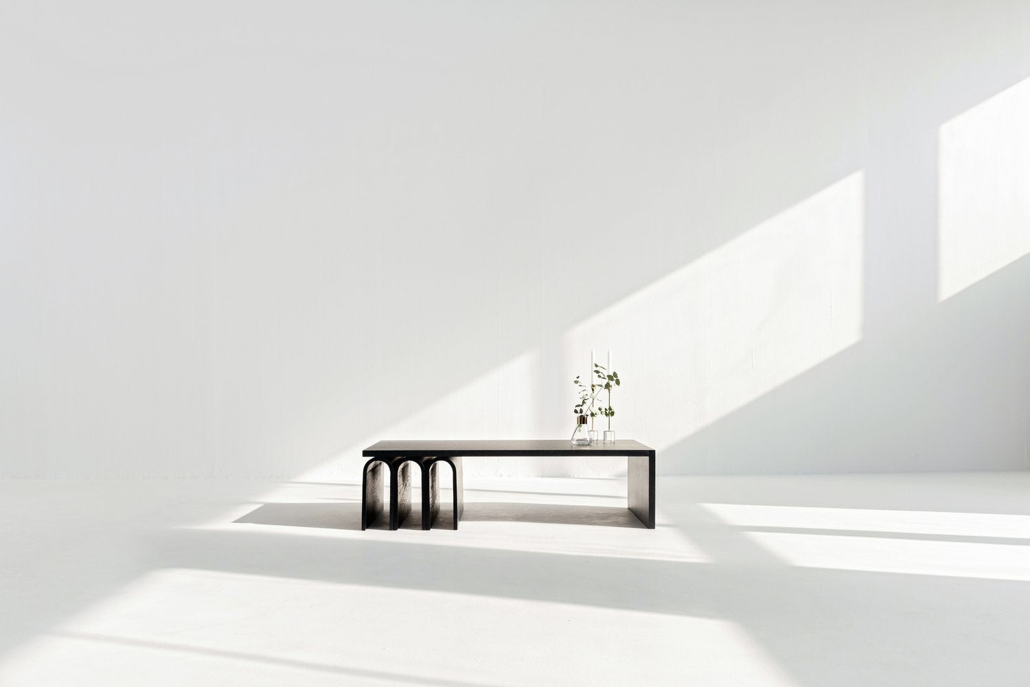 Modern black coffee table in a minimalistic room with light gray walls and white ceiling.