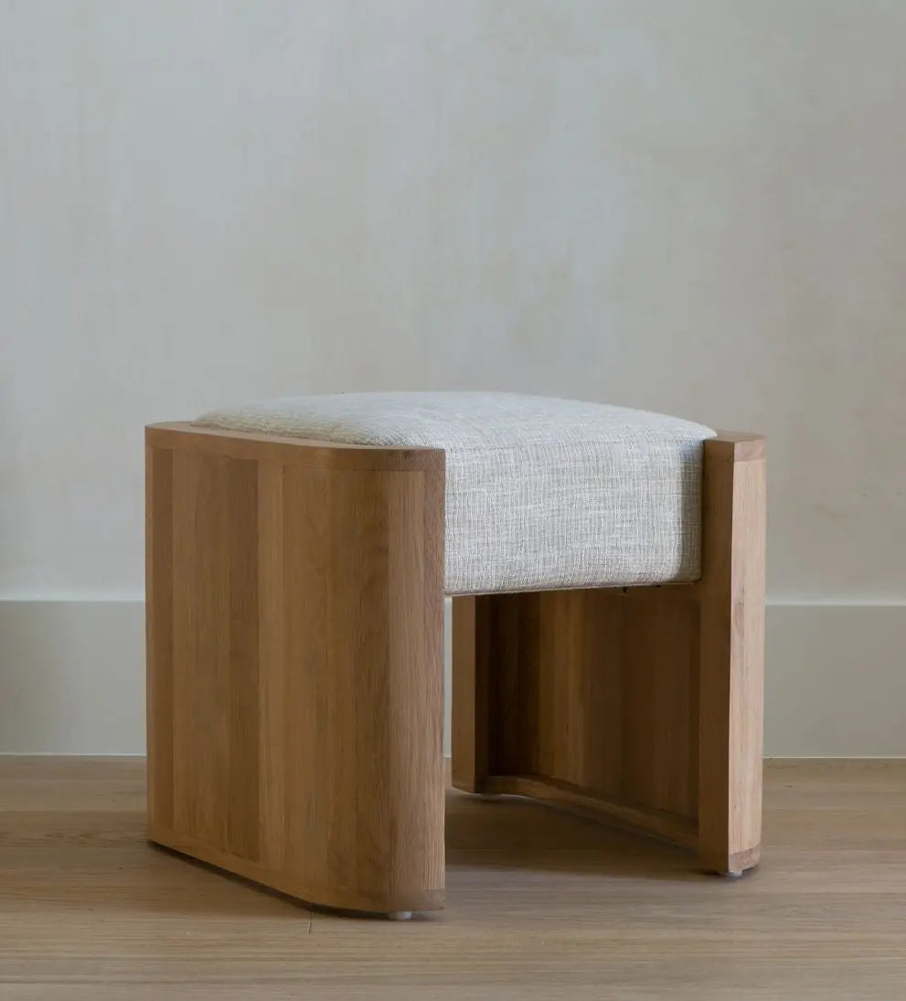 Wooden stool with a cushioned seat on a wooden floor.