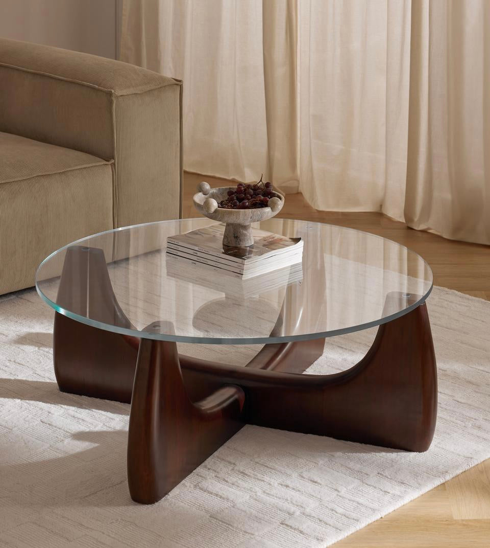 Glass coffee table with wooden base in a living room setting
