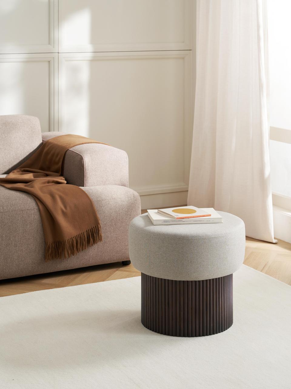 Modern living room with a gray armchair, brown blanket, and a round ottoman.