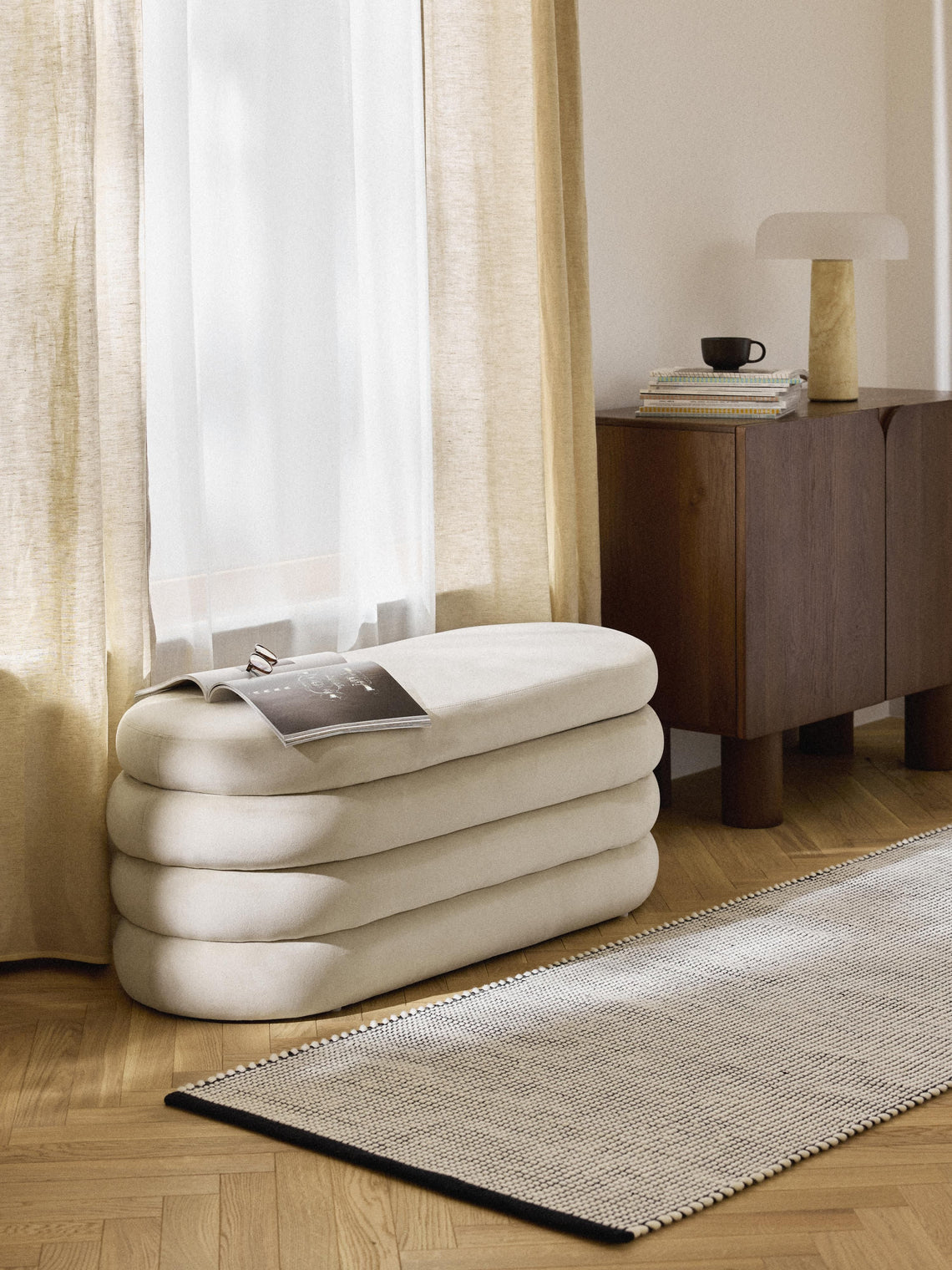 Inflatable modern bench in a room with curtains and a side table.