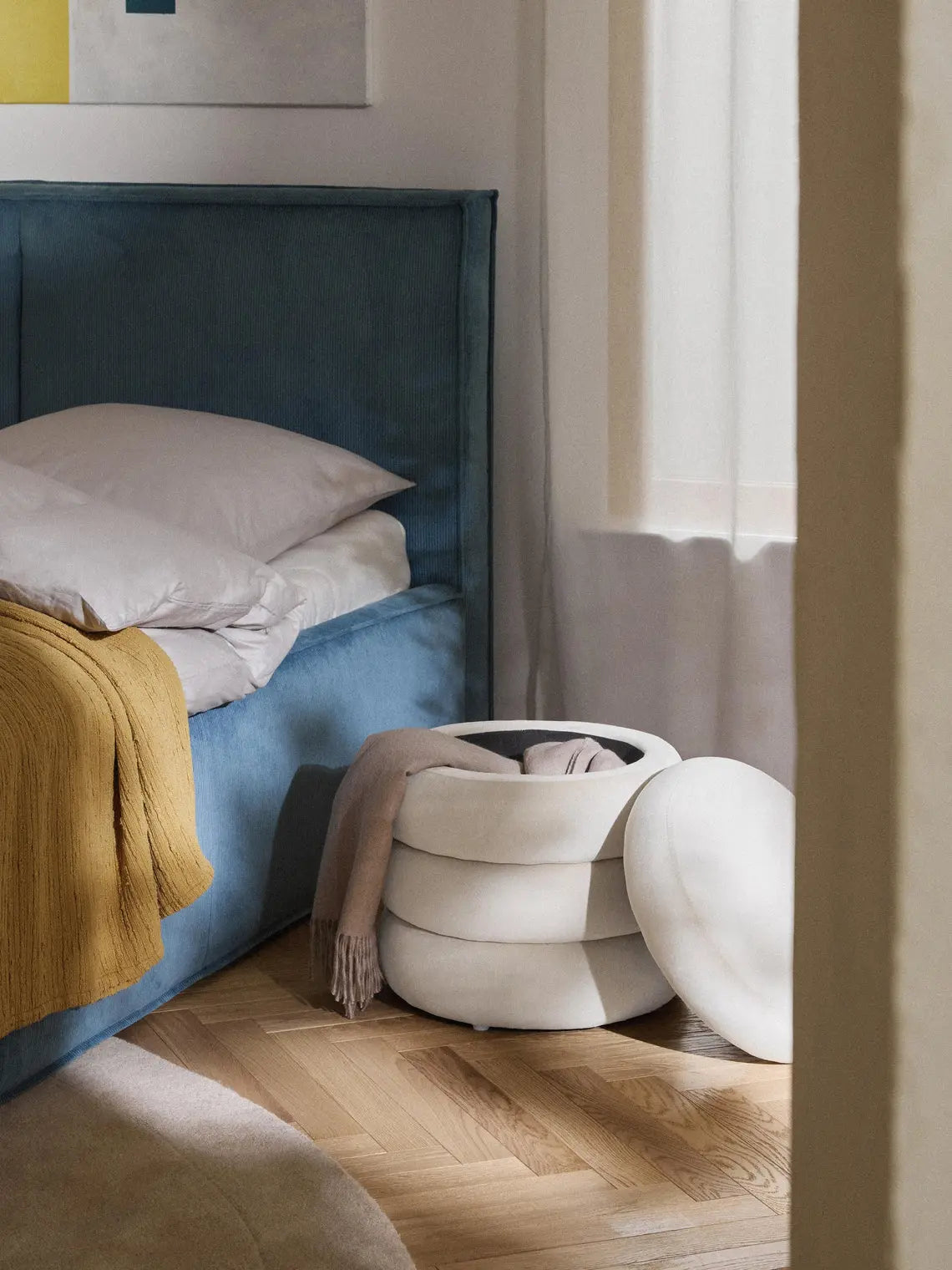 Modern bedroom with a blue upholstered bed and white ottoman