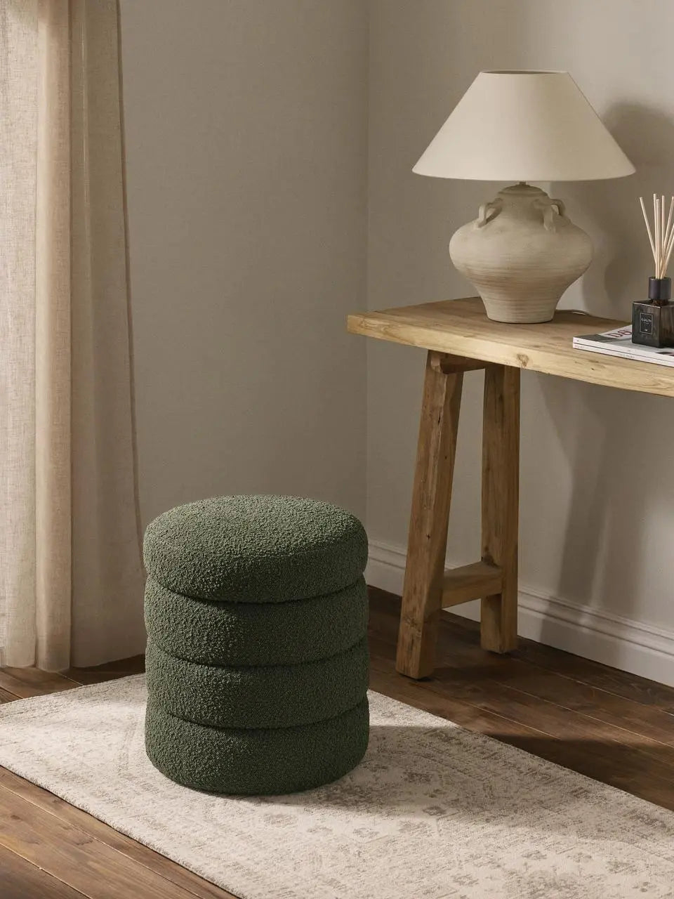 Green textured ottoman in a room with a wooden table and lamp.