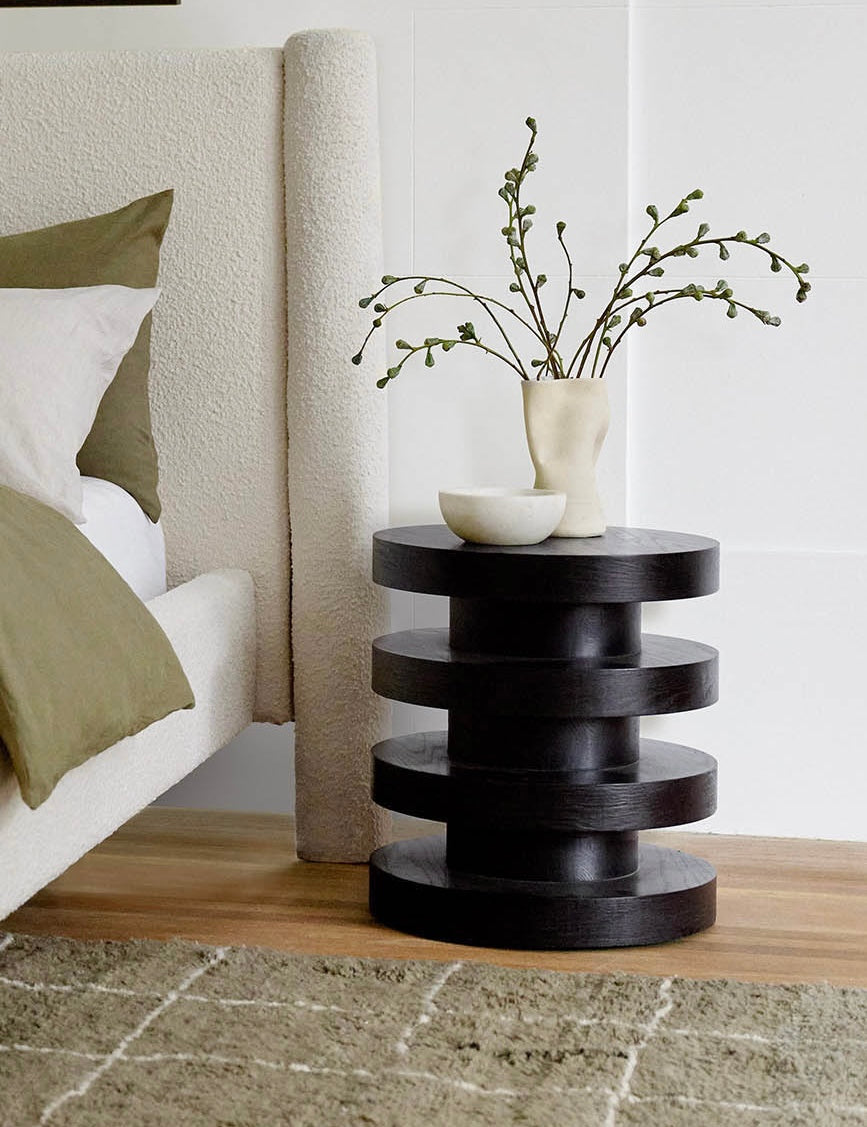 Black round side table with decorative items in a bedroom setting
