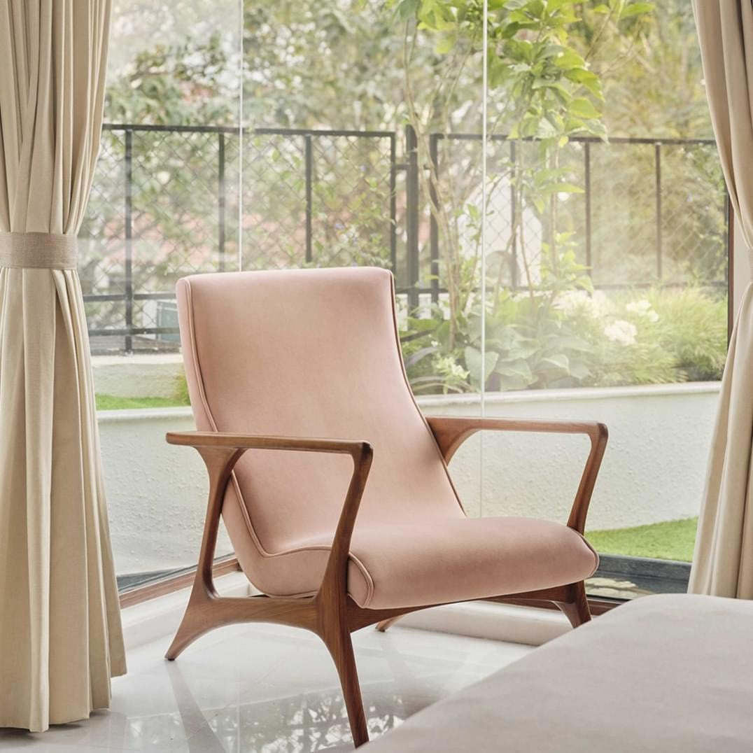 Pink armchair in a room with large windows and curtains