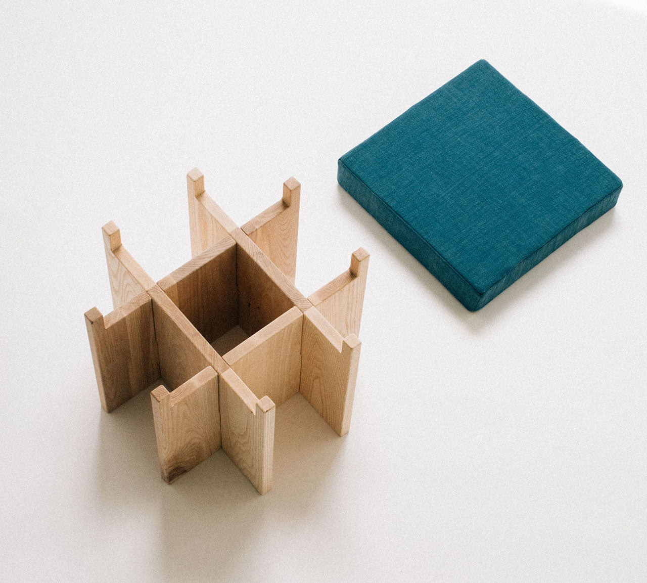 Wooden Stool with teal cushion on a white background