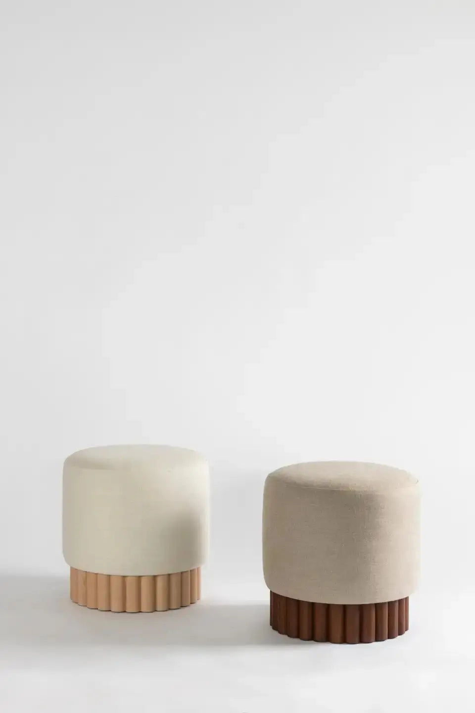Two beige stools with wooden bases on a white background