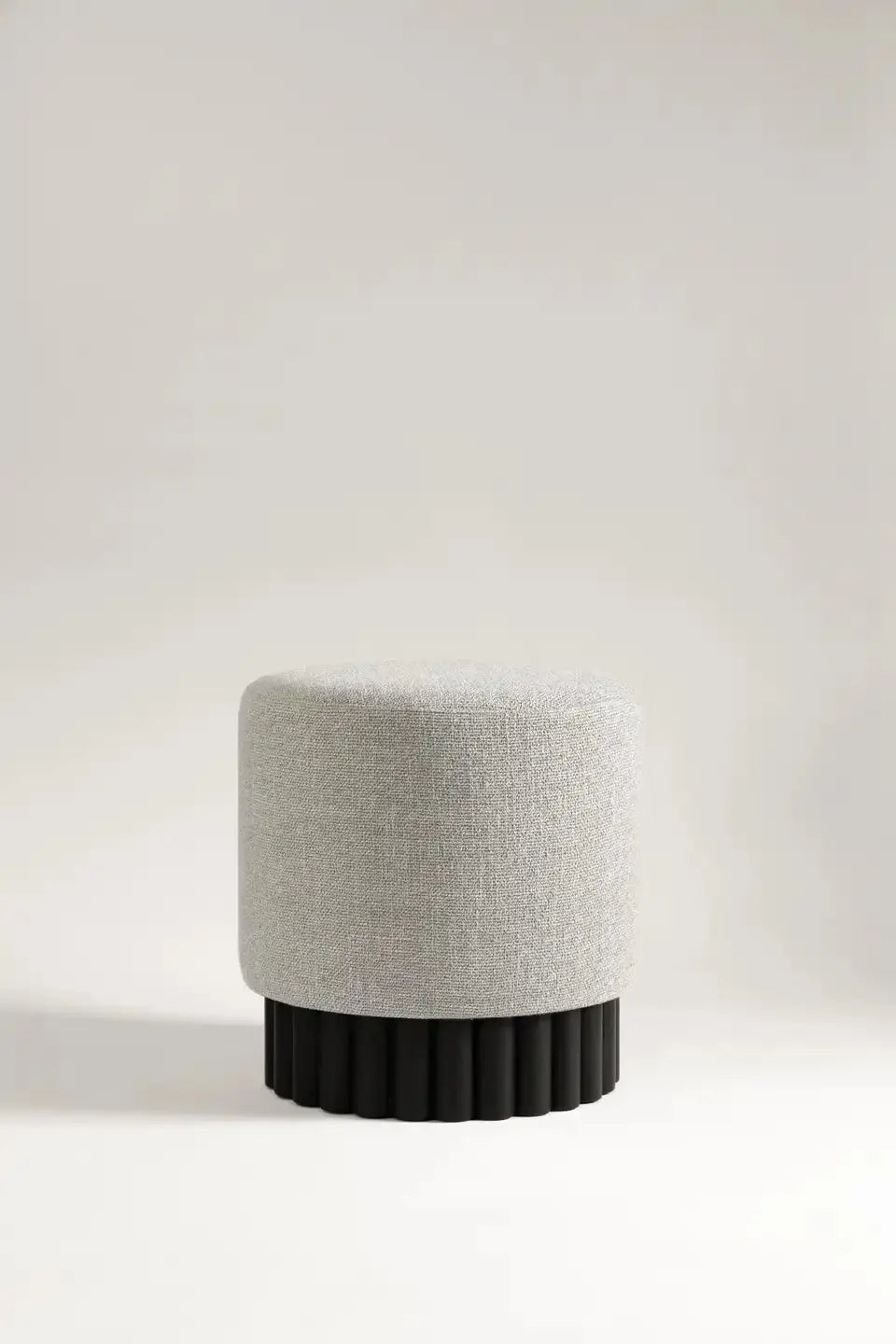 Gray ottoman with black base on a light gray background