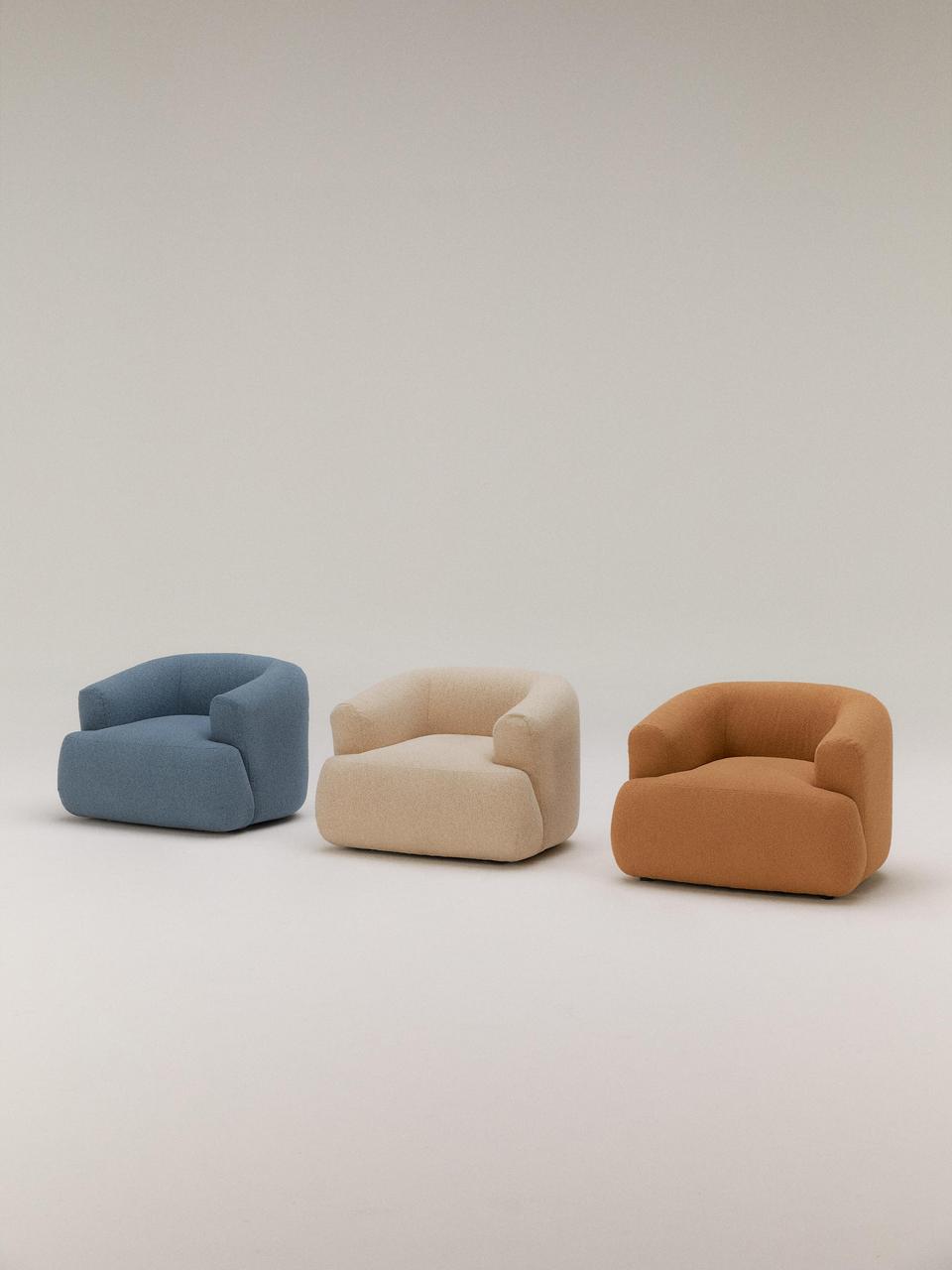 Three armchairs in blue, beige, and brown on a light gray background