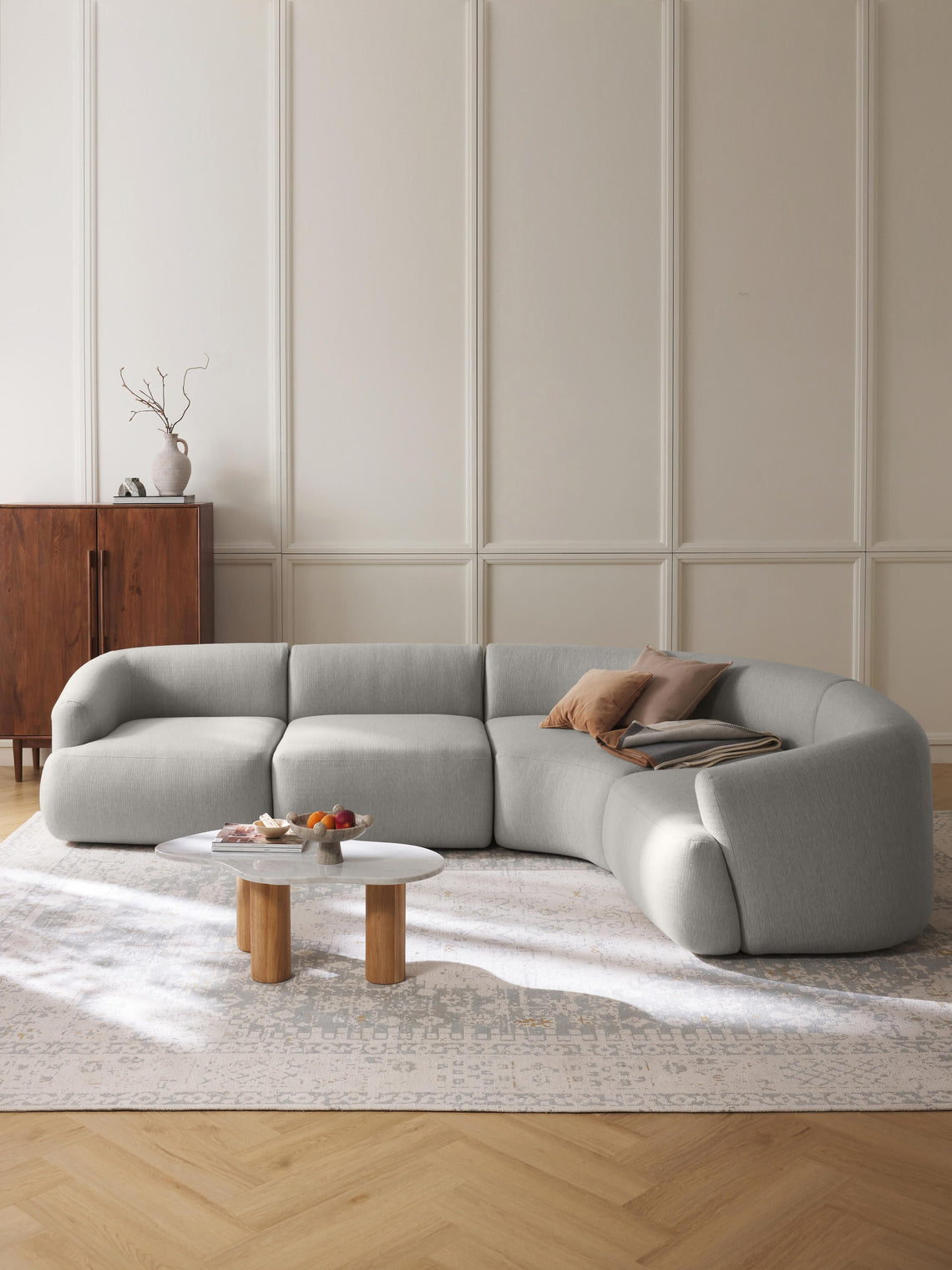 Modern gray sectional sofa in a living room with wooden coffee table and decorative items.