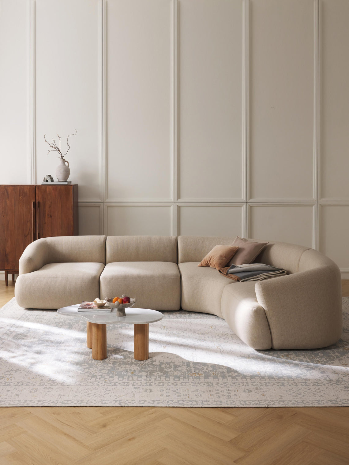 Beige sectional sofa in a living room with a wooden coffee table and decorative items.