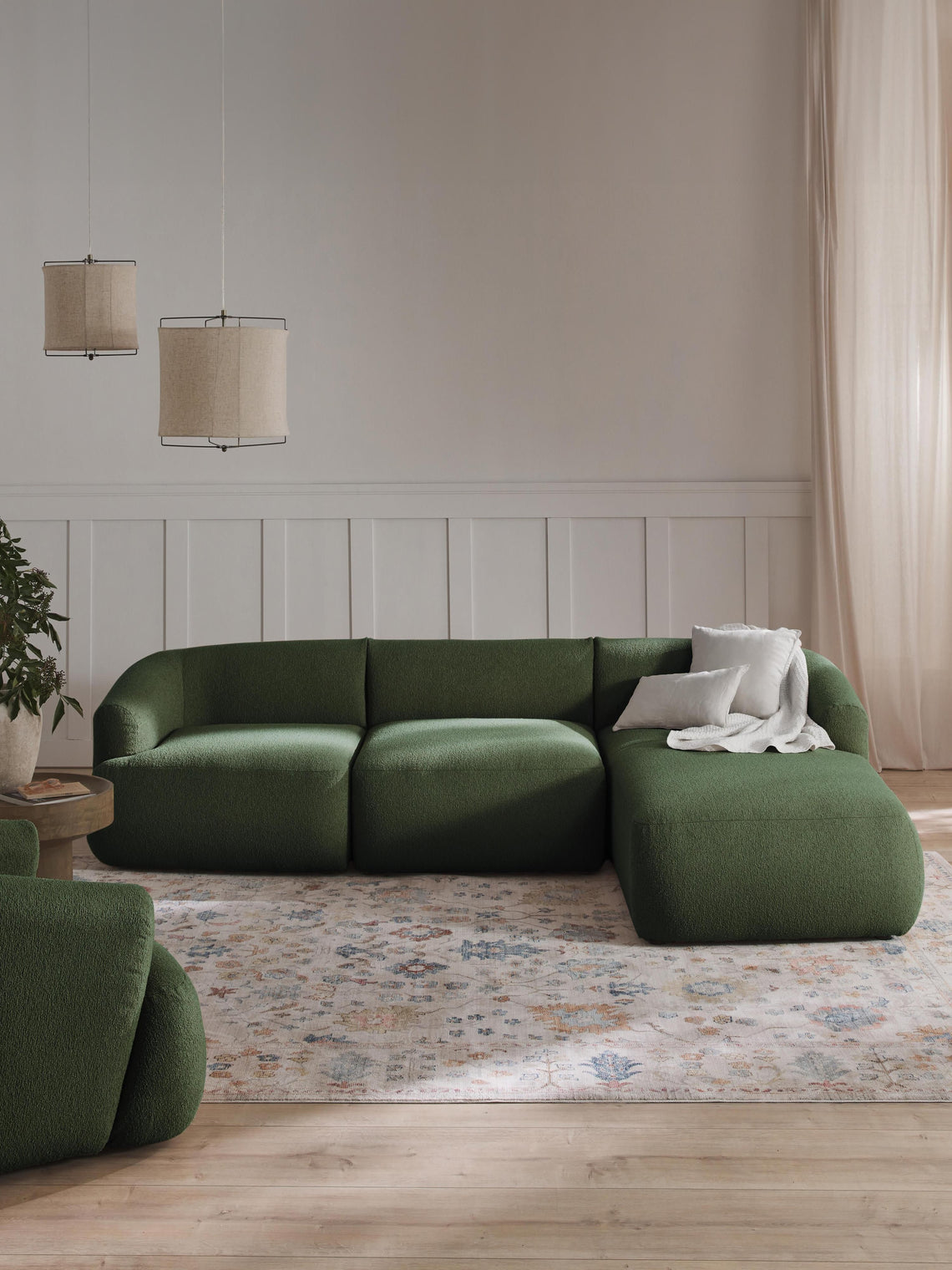 Green sectional sofa in a living room with wooden floor and neutral decor