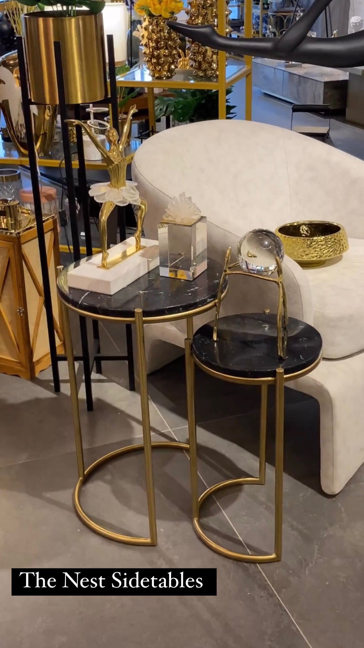 Gold and black side tables with decorative items in a showroom setting.