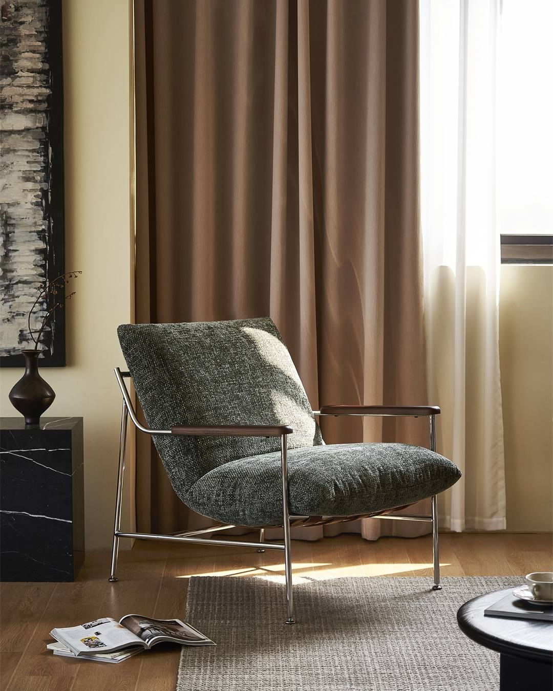 Modern gray armchair in a living room with curtains and a coffee table.