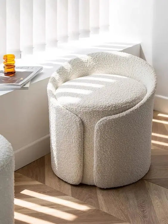 Round, textured ottoman in a room with a window and desk.