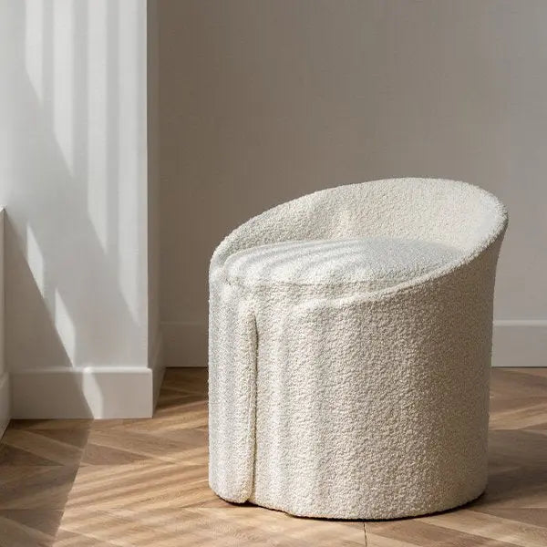 Round, textured stool on a wooden floor with a neutral wall background