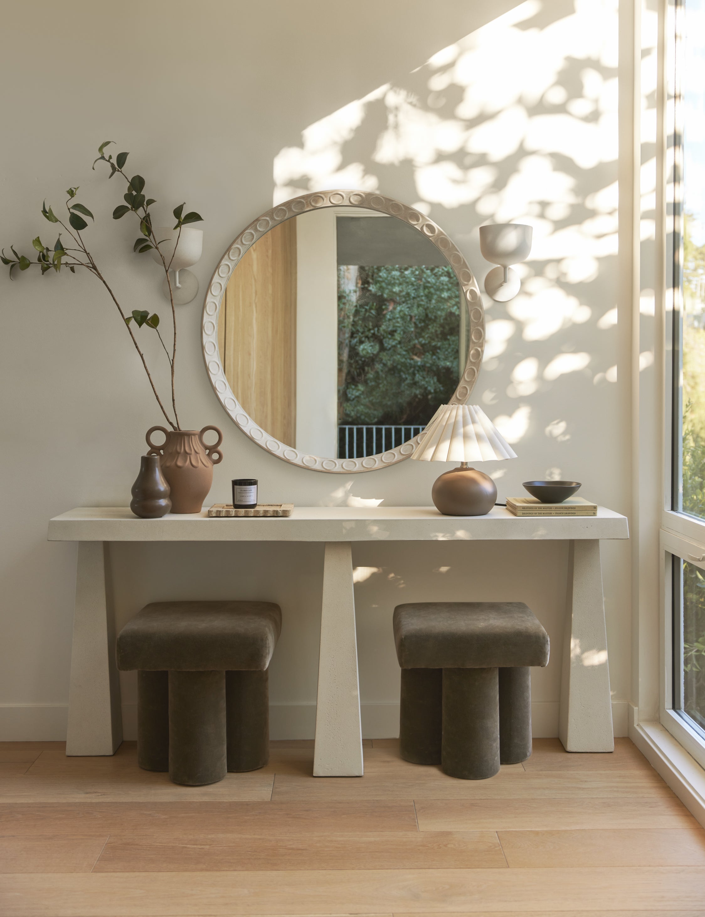 Modern interior with a round mirror, table, and stools in a well-lit room.
