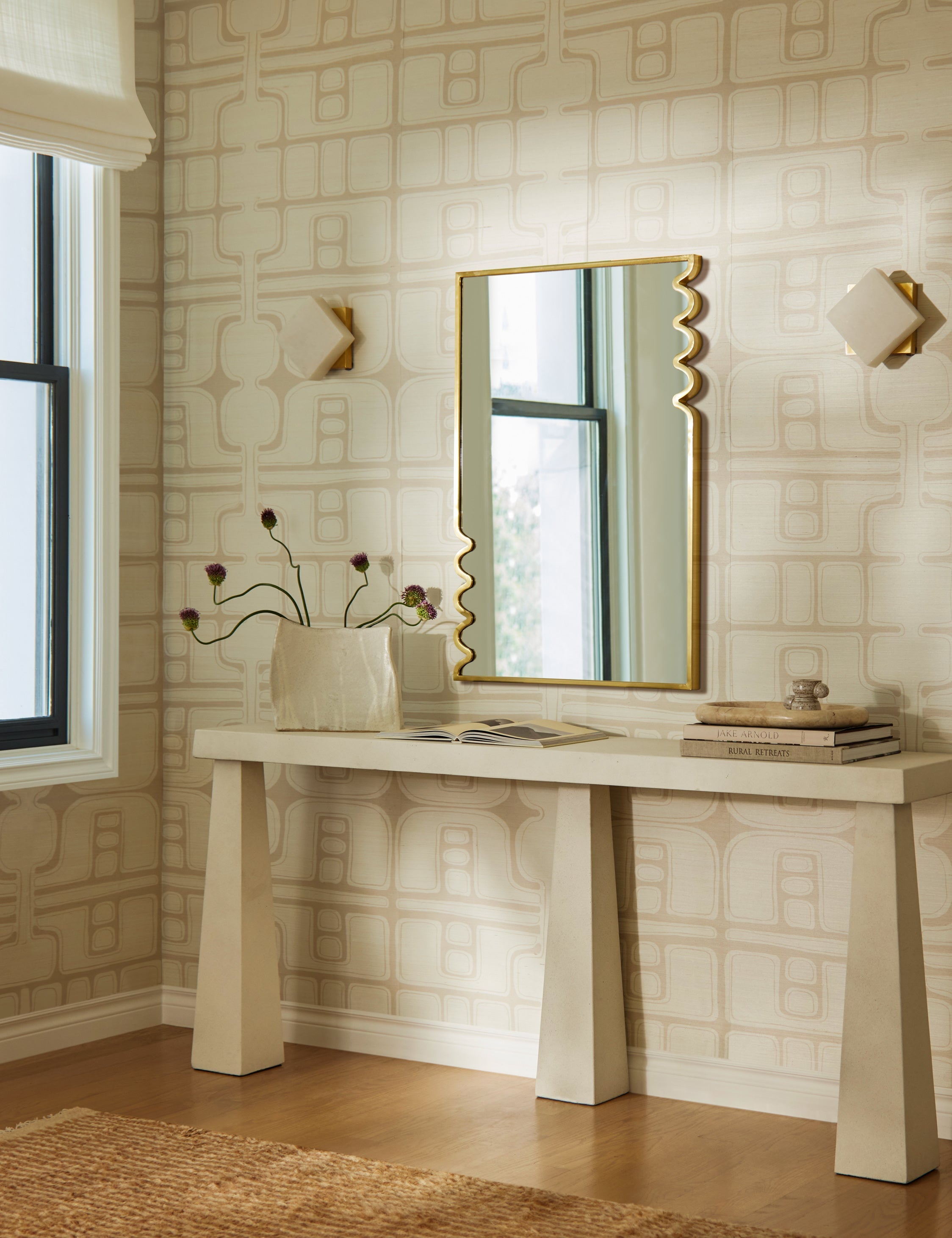 Decorative console table with a mirror against a patterned wall.